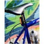 Blue bicycle frame with orange rear safety light mounted on the seat post, against a colorful graffiti wall.