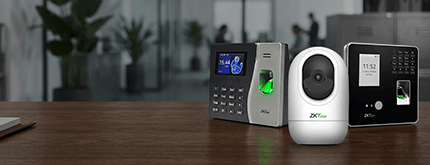 Security access devices on a wooden desk: a fingerprint reader, a video doorbell, and a keypad panel ready for setup in an office.