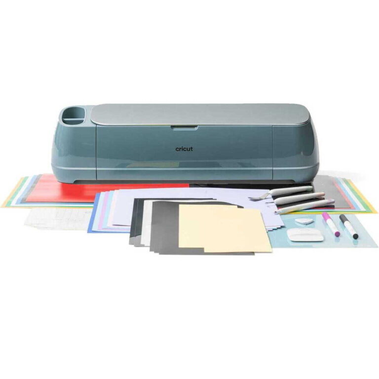Cricut cutting machine with colorful sheets of paper and craft supplies arranged around it for a scrapbooking project