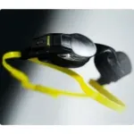 Close-up of black swimming goggles with a bright yellow strap, lying on a light surface.