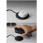 White wireless charging pad with a white charging case on top; a hand holds a smartphone near the pad, ready to charge?ing.