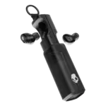 Close-up of a black wireless earbud and its charging case, skull logo visible on the side.