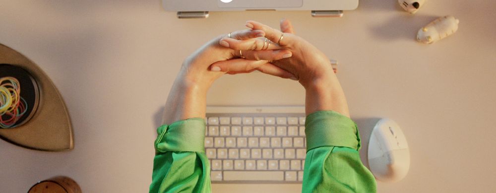 Manos estirándose sobre un escritorio con teclado y mouse